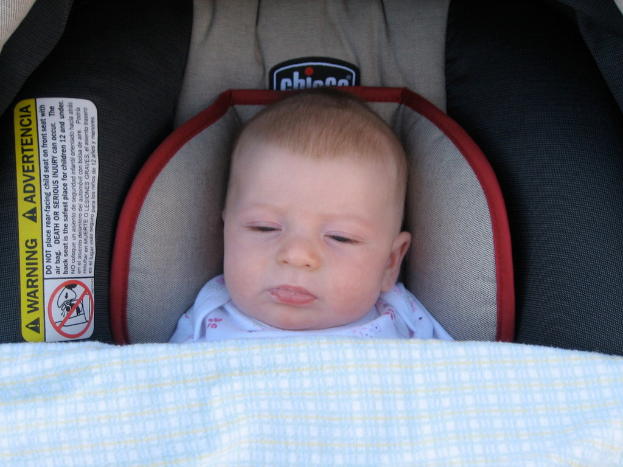 Ein Baby liegt unter einer Babywiege mit einem Warnaufkleber auf der linken Seite der Wiege.