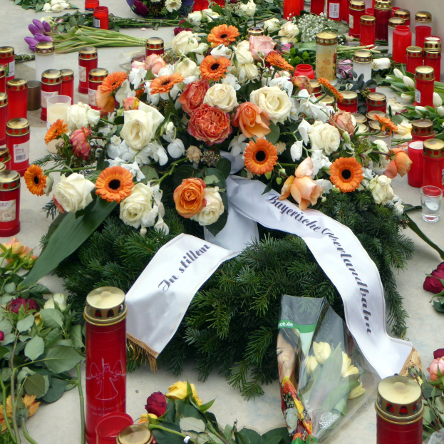 Mahnmal in Berlin mit Blumen und Kerzen vor einer Wand