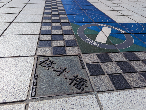 Ein gefliestter Boden mit einer Tafel, auf der "Yokohama" steht, und einem Brett mit Text darauf.