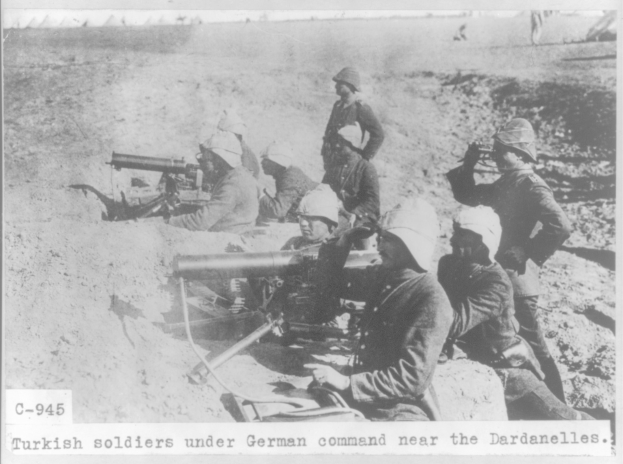 Schwarzes und weißes Foto von türkischen Soldaten unter deutschem Kommando in der Nähe der Dardanellen, die Helme tragen und Waffen halten, mit Text unten.