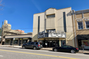 Außenansicht des Feinschmecker-Theaters in St. Louis, Missouri, mit Fahrzeugen auf der Straße, einem Fußgänger auf dem Gehweg, einem Wegweiser, Bäumen, benachbarten Gebäuden und dem Himmel.