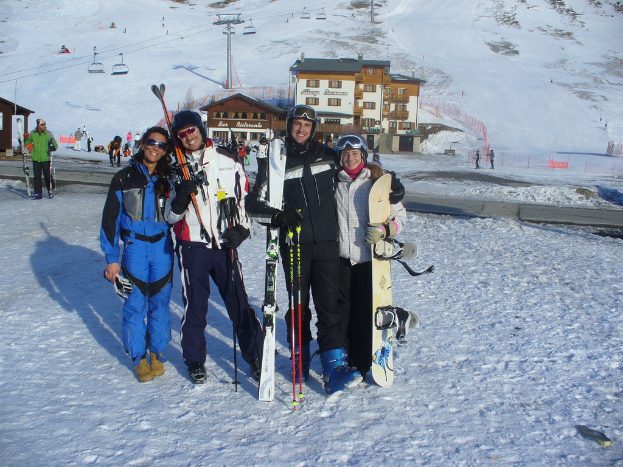 Vier Personen posieren mit Skaterausrüstung und Werkzeug vor einer winterlichen Bergkulisse.