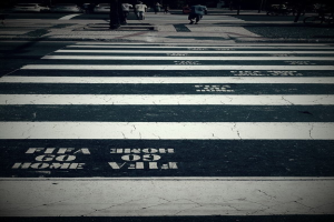 Eine Zebrastreifenübergang mit ein paar Menschen, die darüber gehen, und ein paar Autos in der linken oberen Ecke.