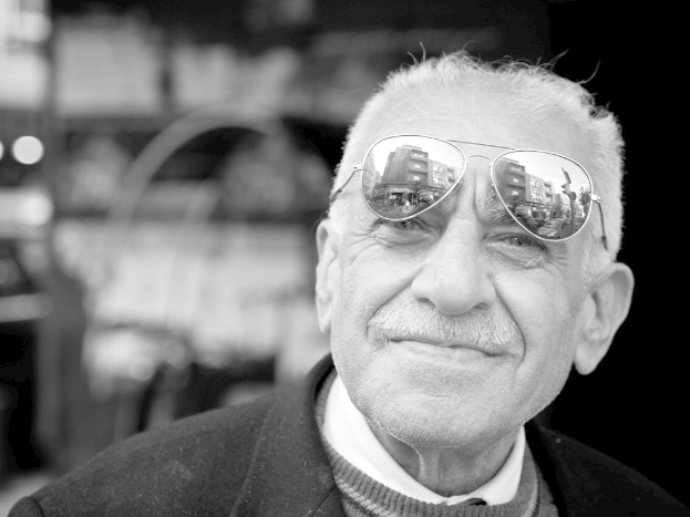 Ein Mann mit einem lachenden Gesicht, der eine Brille trägt, mit einem unscharfen Hintergrund.