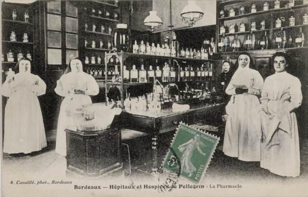 Ein Schwarz-Weiß-Foto einer Gruppe von Frauen, die um einen Tisch in einer Apotheke stehen, mit verschiedenen Gegenständen auf dem Tisch und Regalen voller Flaschen im Hintergrund, mit Text und einem Stempel unten auf dem Bild.