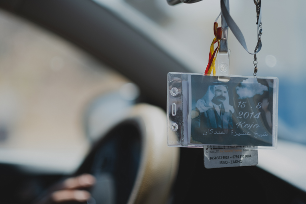 Eine Person fährt ein Auto mit einem ID-Kartenhalter am Lenkrad, ihre Hand ist auf der linken Seite zu sehen, mit einem unscharfen Hintergrund.