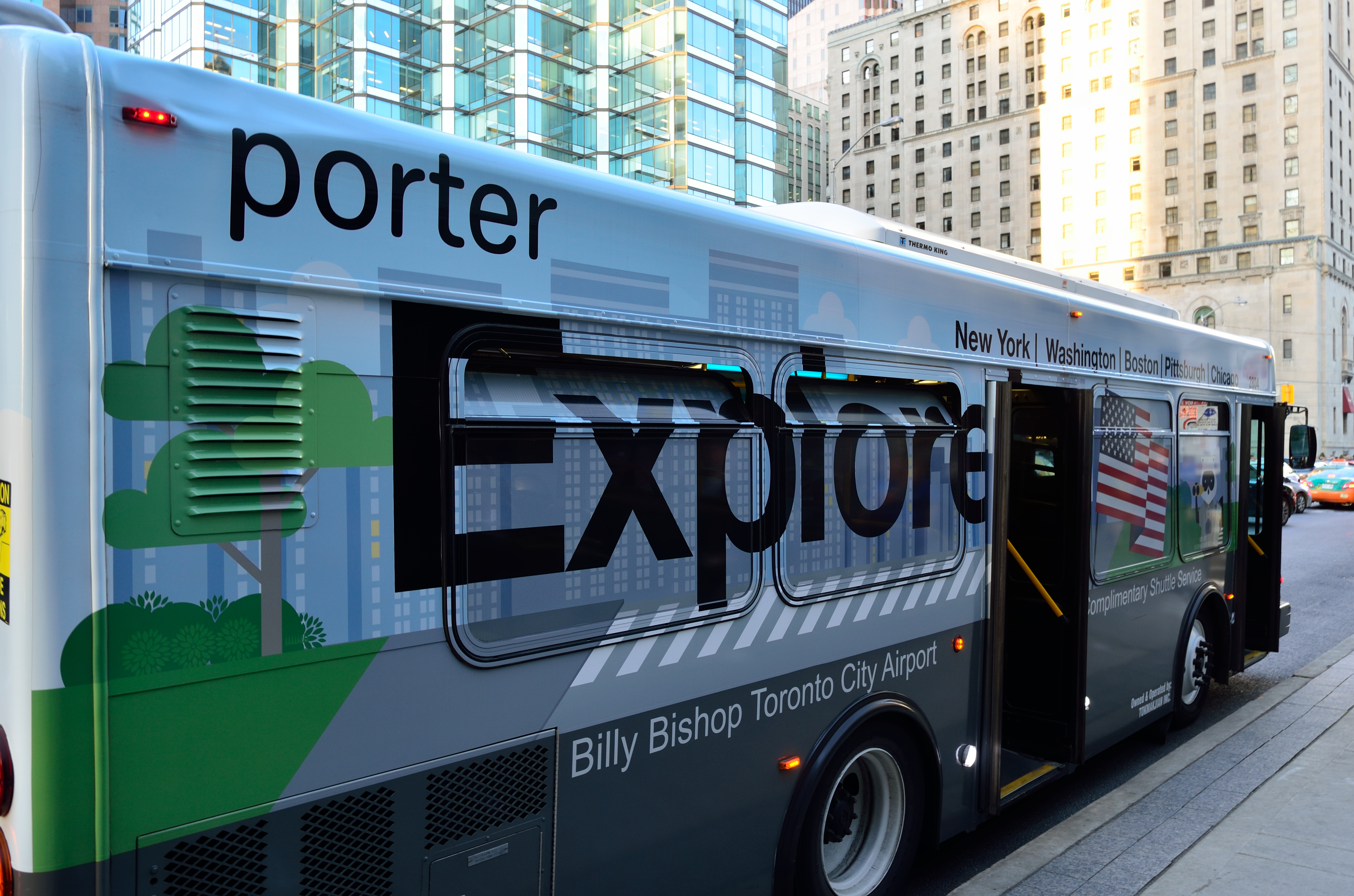 Ein Porter Express Bus steht auf der Seite einer Stadtstraße, umgeben von hohen Gebäuden, mit einem Fußweg auf der rechten Seite.