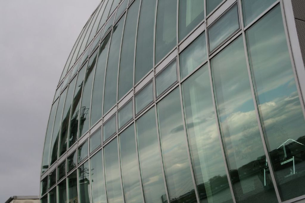 Ein großes Glas-Gebäude mit einem blauen Himmel im Hintergrund.