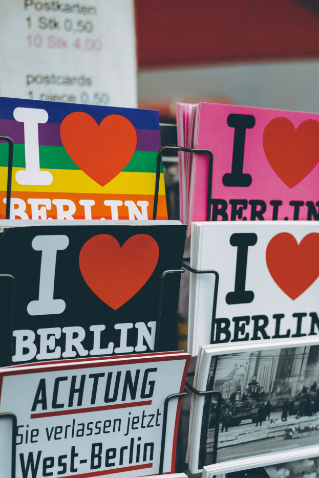Ein Ständer mit verschiedenen Büchern und Plakaten mit der Aufschrift "Ich liebe Berlin" vor einem leicht unscharfen, träumerischen Hintergrund.
