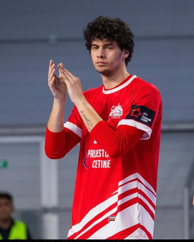 Ein Mann in einem roten und weißen T-Shirt klatscht im Vordergrund mit einer anderen Person und einer Wand im Hintergrund, mit dem Text "Copenhagen Futsal Club - Foto 1" unten.