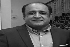 Ein Mann im Anzug steht vor einer Treppe und sieht besorgt aus, mit einem ernsten schwarz-weißen Hintergrund.