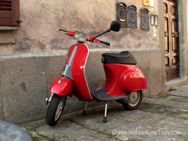 Ein roter E-Scooter steht vor einem Haus mit Tür und Fenstern auf einer Straße mit etwas Text unten.
