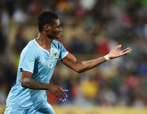 Ein Fussballer in einem blauen Trikot feiert mit ausgestreckten Armen, mit einem unscharfen Hintergrund.