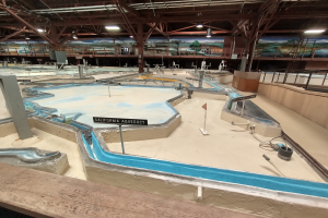 Ein großes Indoor-Wasserpark mit zahlreichen Wasserrutschen, einem Minigolfplatz, beleuchteter Decke und Wandgemälden.