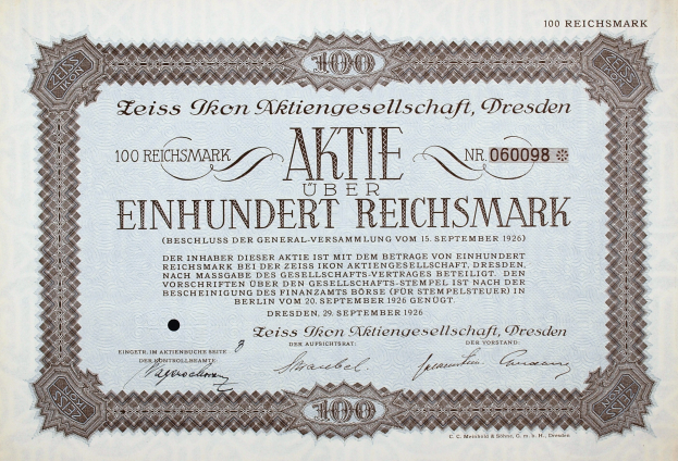 Ein altes deutsches Aktienzertifikat mit schwarzem Rand, auf dem der Text 'Aktie über Einhundert Reichmark' steht.