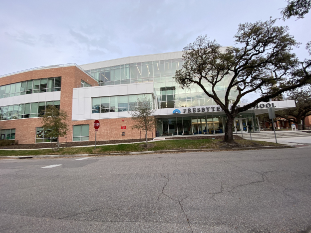 Großes, zweistöckiges Backsteingebäude mit vielen Fenstern, beschriftet mit 'Presbyte Middle School', umgeben von Bäumen, Rasen, Schildern, Strommasten und einer Straße unter einem bewölkten Himmel.