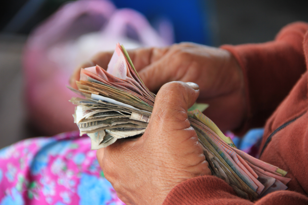 Eine Frau mit einem Bündel Geld in den Händen, mit einem unscharfen Hintergrund.