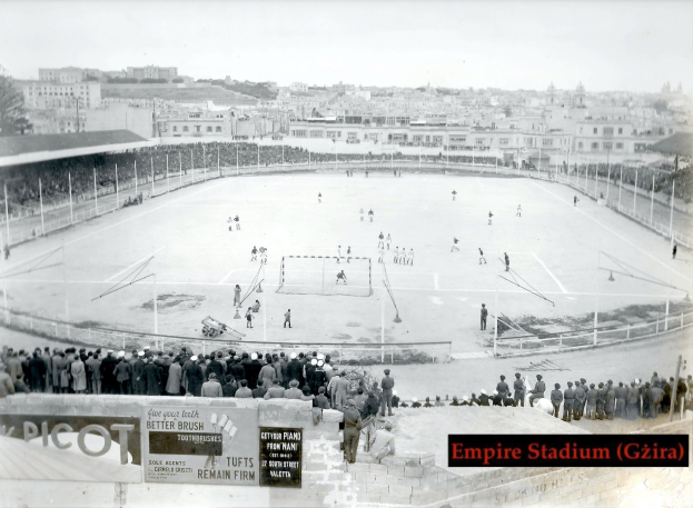 Ein altes Schwarz-Weiß-Foto des Empire Stadiums in Giza mit einer Gruppe von Menschen, die in der Mitte Eishockey spielen, umgeben von einem Zaun, Gebäuden und Bäumen im Hintergrund und Text am unteren Rand.