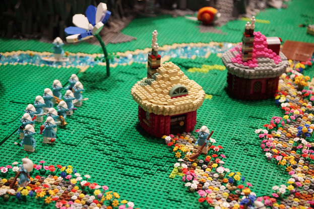 Ein Lego-Modell einer Kleinstadt mit Häusern, Blumen, Pflanzen und verschiedenen Spielzeugen, mit einem sanft unscharfen Hintergrund, der einen träumerischen Effekt erzeugt.