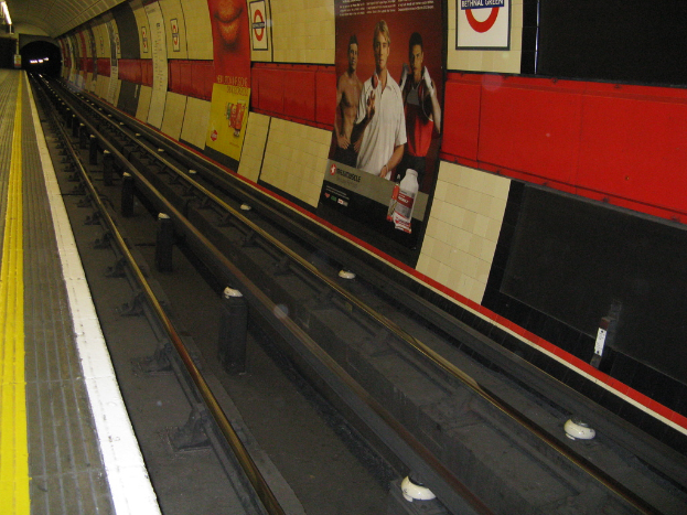 Eine Bahnstrecke mit Plakaten an der Wand daneben.