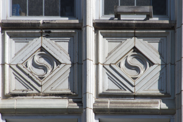 Nahaufnahme einer Gebäudefassade mit zwei Glasfenstern und einer Holztür.