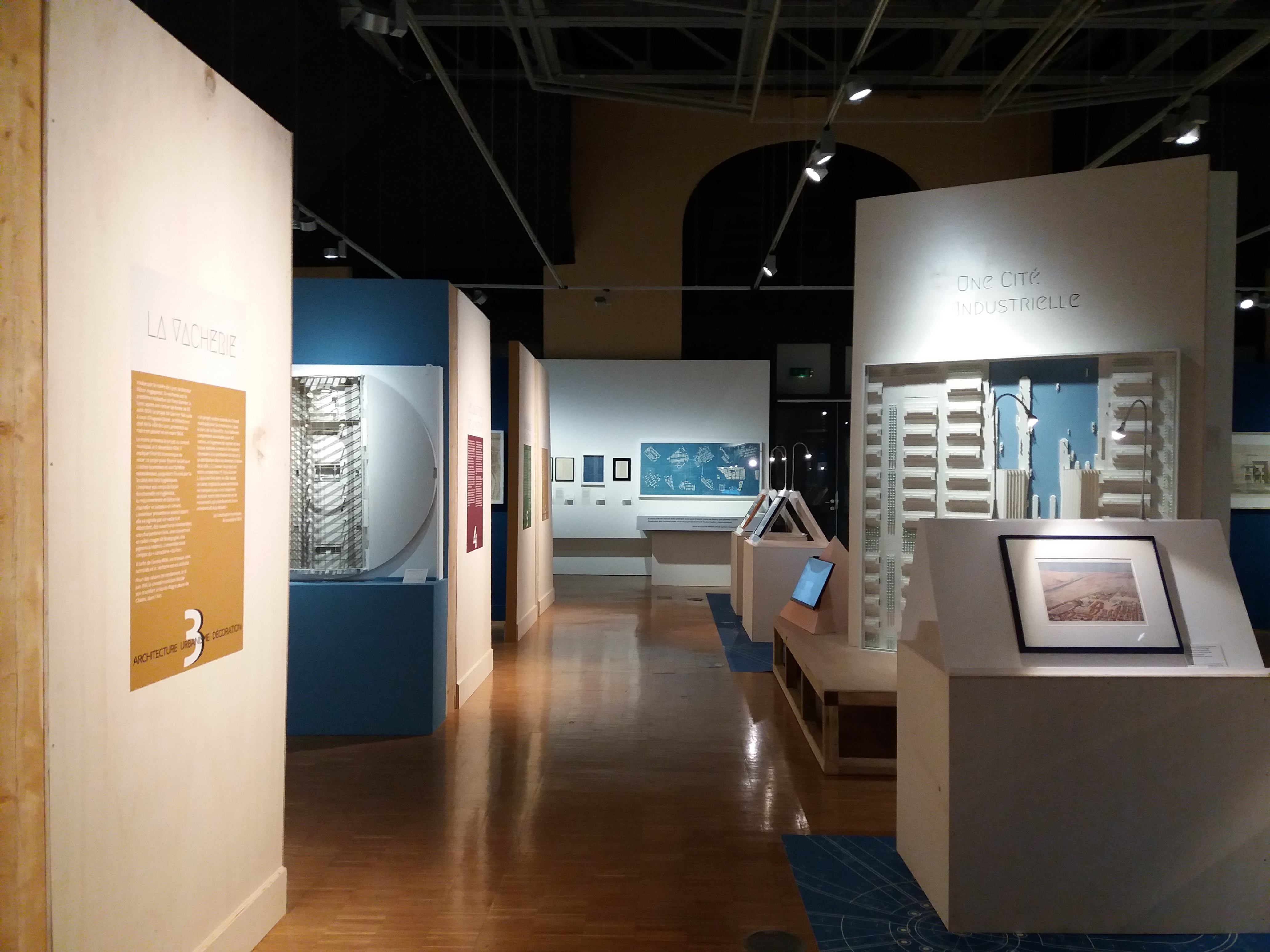 Ein Raum voller verschiedener Kunstwerke, darunter Fotorahmen auf Tischen, Texttafeln an den Wänden, Deckenleuchten und ein Teppichboden, im Museum of Modern Art Ausstellung.