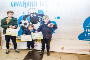 Drei Kinder halten Papiere vor einem Banner