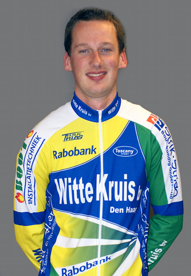 Ein Sportler in einem Trikot mit verschiedenen Sponsorennamen posiert für ein Foto.