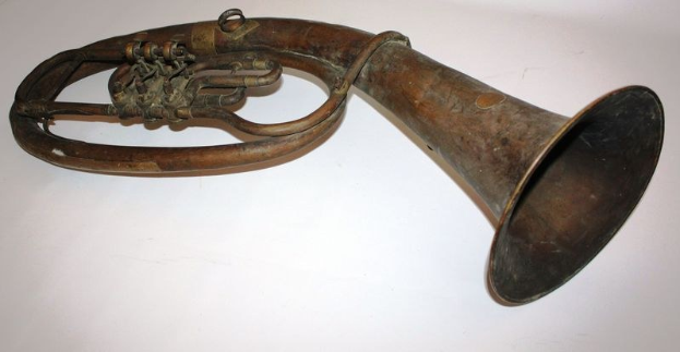 Altes Messinghorn mit glänzender Oberfläche, gebogenem Hals und aufgeblasenem Schalltrichter, verziert mit kunstvollen Gravuren auf einem weißen Hintergrund.